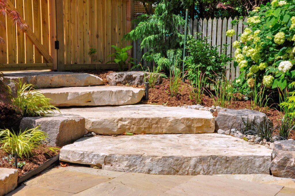 A well constructed stone staircase leading up to a vibrant garden featuring various plants and flowers