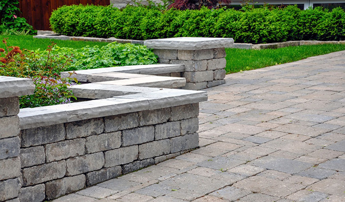 Beautifully Crafted Brick Patio With Stone Benches And A Flower Bed, Highlighting Top-notch Hardscaping And Landscape Installation Services