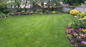 A vibrant backyard featuring a lush green lawn surrounded by colorful blooming flowers.