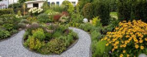A gravel path winding through a vibrant garden filled with colorful flowers and lush shrubs