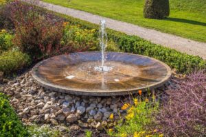 A serene garden fountain surrounded by colorful flowers and rocks creating a tranquil atmosphere