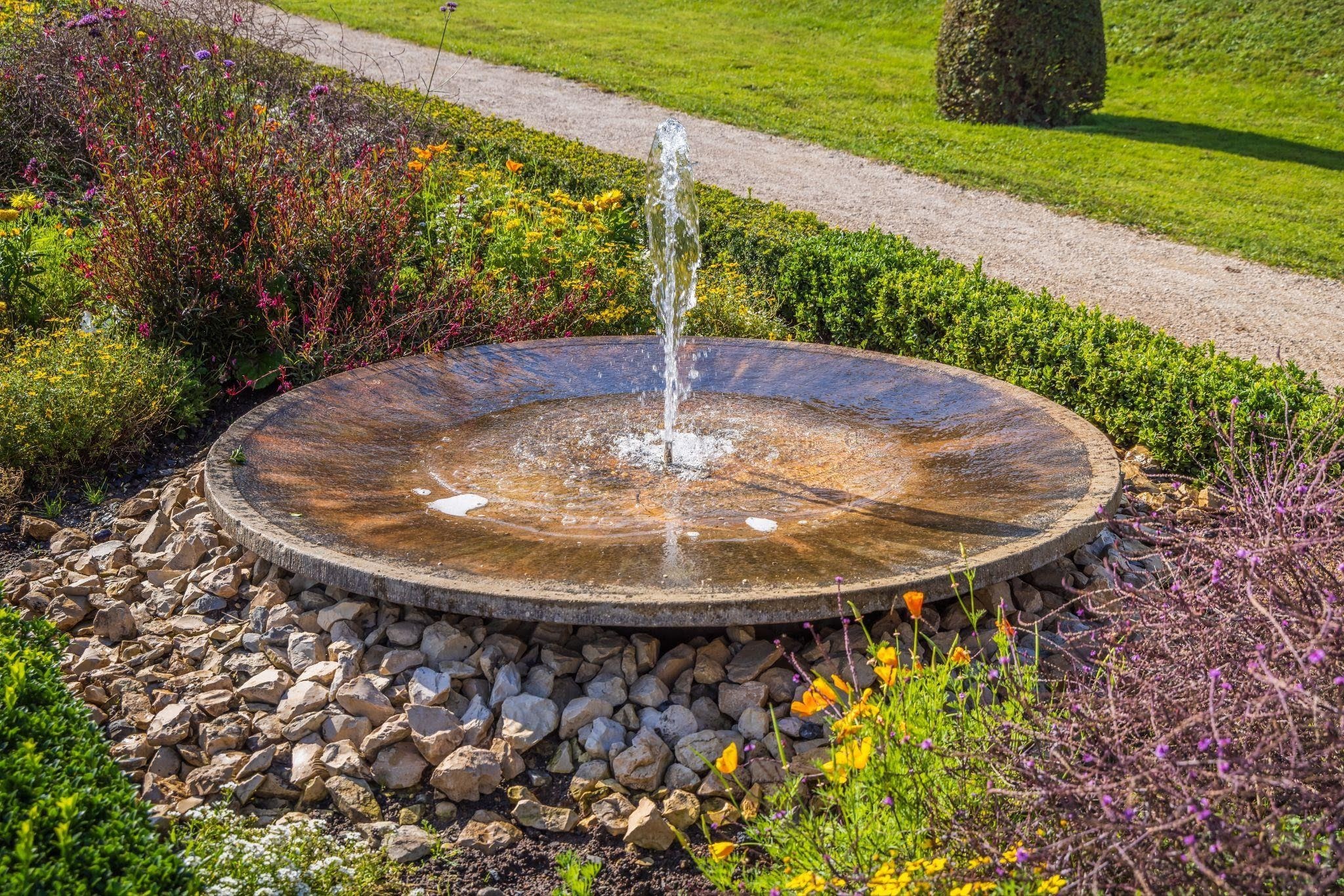A serene garden fountain surrounded by colorful flowers and rocks creating a tranquil atmosphere